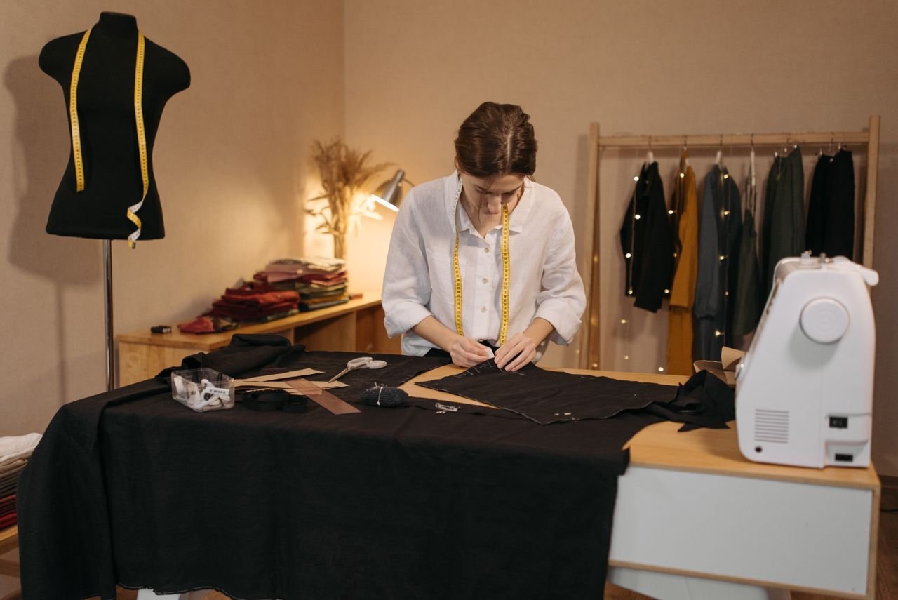Home Fashion designer working on fabric with sewing tools in a creative studio environment.